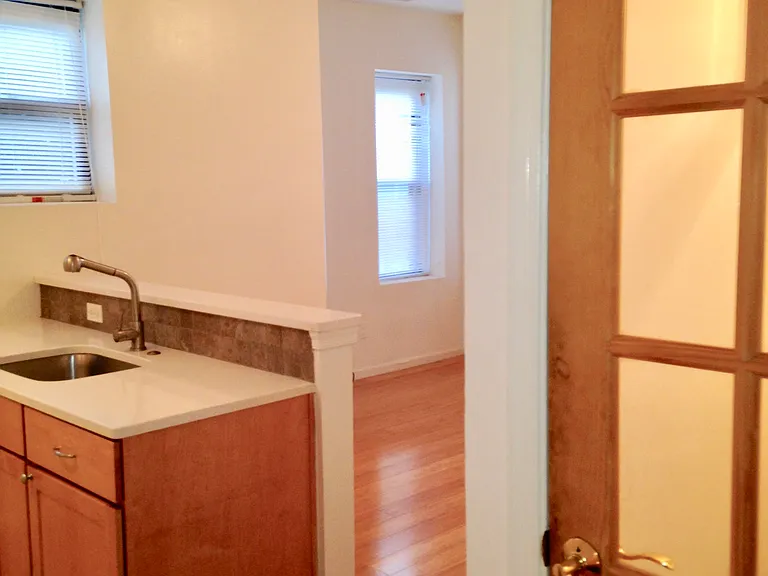 View of entrance door inside living space, partial view of kitchen and living room.