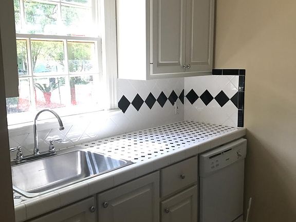 The kitchen sink with another window and the beautiful, retro, black and white tile.