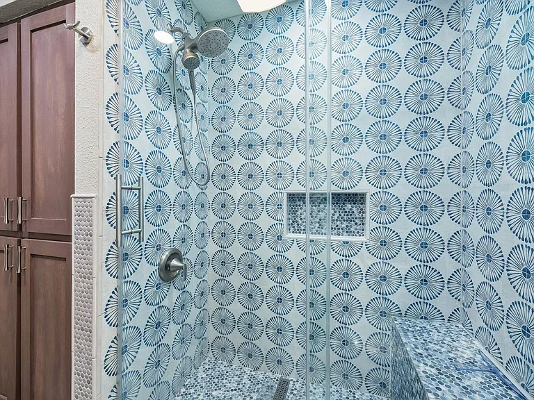 Tiled shower featuring a glass enclosure, built-in shelving, a shower bench, and brushed nickel fixtures