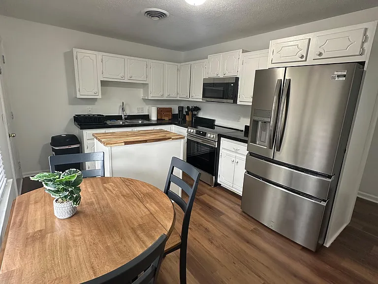 Functional kitchen with ample cabinet storage, stainless steel appliances, and an island for prep or casual dining.