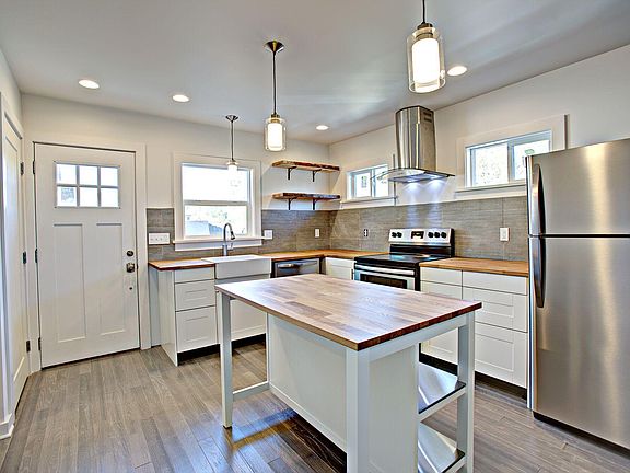 Beautiful kitchen with island/added storage, butcher-block countertops, apron-front sink, dishwasher, stainless steel refrigerator and range, tile backsplash, blue pine, live-edge shelves, large lazy susan and pantry