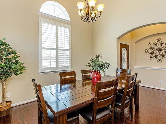 The formal dining room is spacious, has high ceilings and a beautiful plantation shuttered palladium window with views of the front yard. Note the beautiful builder details including the large arched room opening and pretty oversized art niche in the