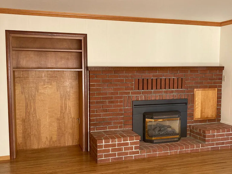 Living room with built in cabinet, brick gas fire place.