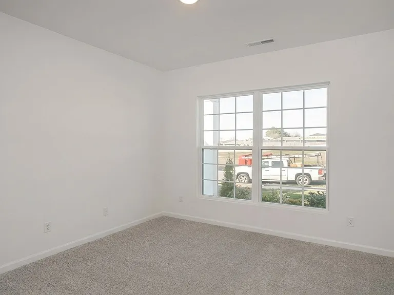 Versatile main-level bedroom featuring a large window that floods the space with natural light, perfect as a home office, guest suite, or bedroom.