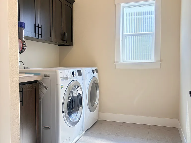 Laundry room with washer, dryer, sink, and cabinets.