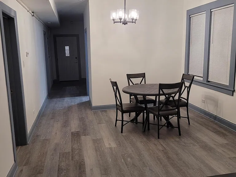 Dedicated dining area with a round table, overhead chandelier, and nearby windows with blinds for everyday meals.