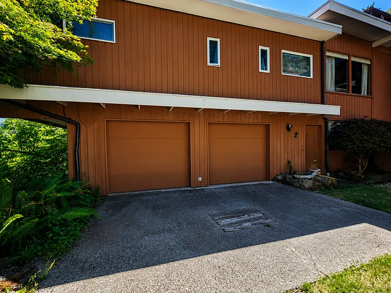 The unit includes 1 car bay in the garage and additional parking outside. The door to the right of the garage leads to the base of the stairs shown earlier.
