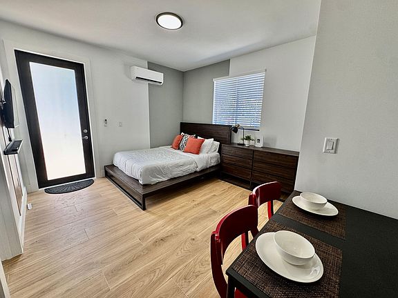 Well-appointed bedroom featuring a platform bed, dresser storage, window blinds, and efficient mini-split A/C.