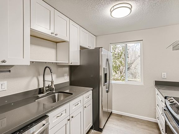 Kitchen with all stainless steel GE appliances, quartz grey countertops, shaker cabinets, and all matching brushed nickel fixtures