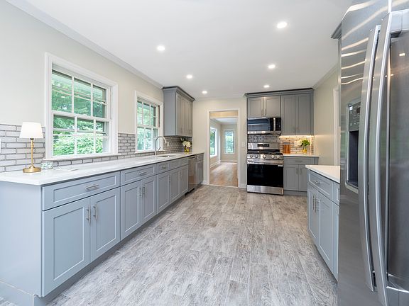 Beautiful kitchen with recessed lighting, new appliances and quartz surfaces with glass backsplash.