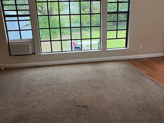 Large window in main room with view of backyard and trees. New blackout roller blinds window coverings for privacy.