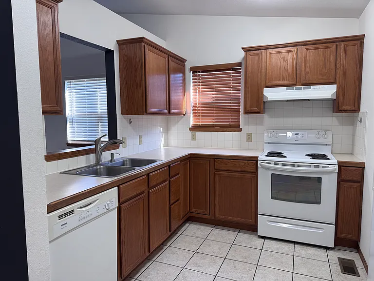 Kitchen with dishwasher, stove and to the right is the refrigerator with ice and water in the door.