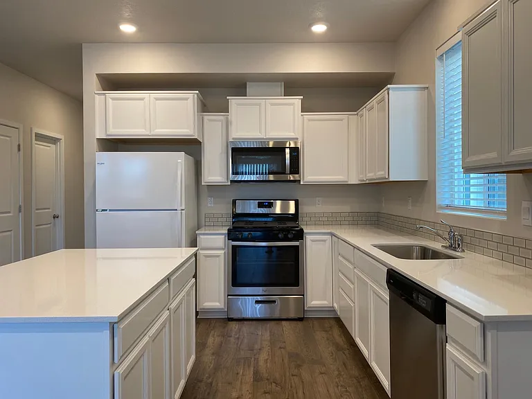 Kitchen with quartz countertops and SS appliances.