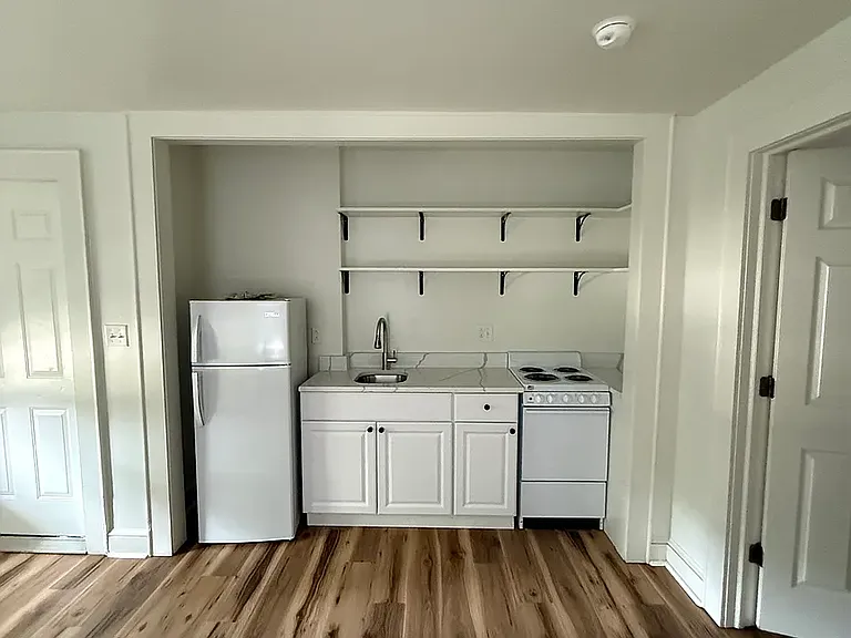 Unit B - Living Room & Kitchen view. Kitchen has new appliances, including the oven/stove, sink, and refrigerator.