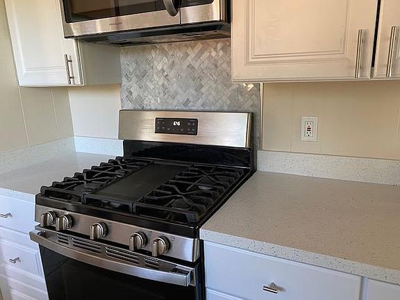 Gas stove with marble back splash. Microwave / fan over stove