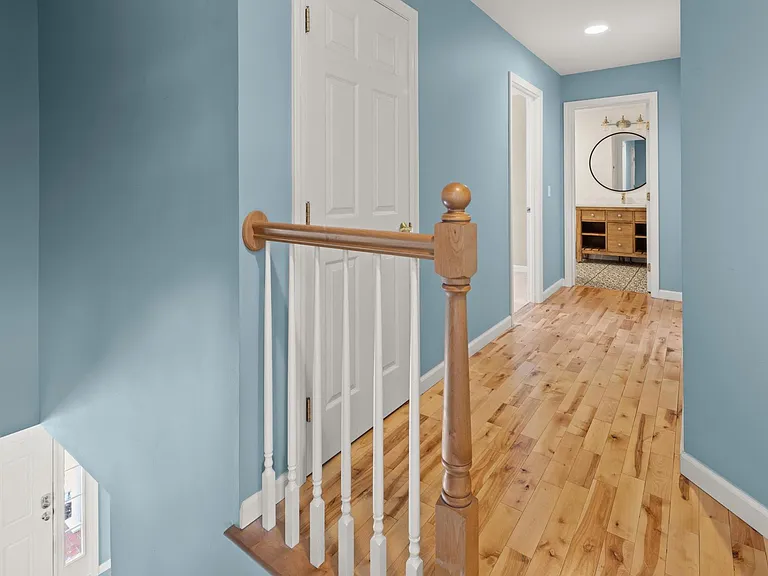 Upstairs hallway. The photo was taken from the top of the stairs/entrance to the primary bedroom looking at the linen closet, two bedrooms, and bathroom at the end of the hallway.