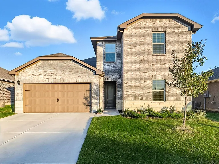 View of front of home featuring brick siding, a garage, a front lawn, and concrete driveway