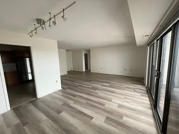 Kitchen entrance, dining and living area with new hardwood floor and studio lighting.