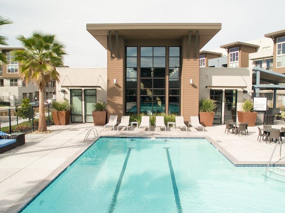 Aspire Apartments Tracy California Luxury Living A large swimming pool in front of a building with palm trees.