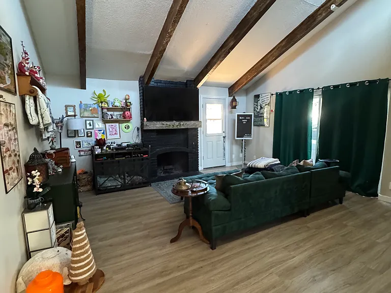 The sliding glass door behind the green curtains leads to the private parking for the home. The Back door leads to the private deck