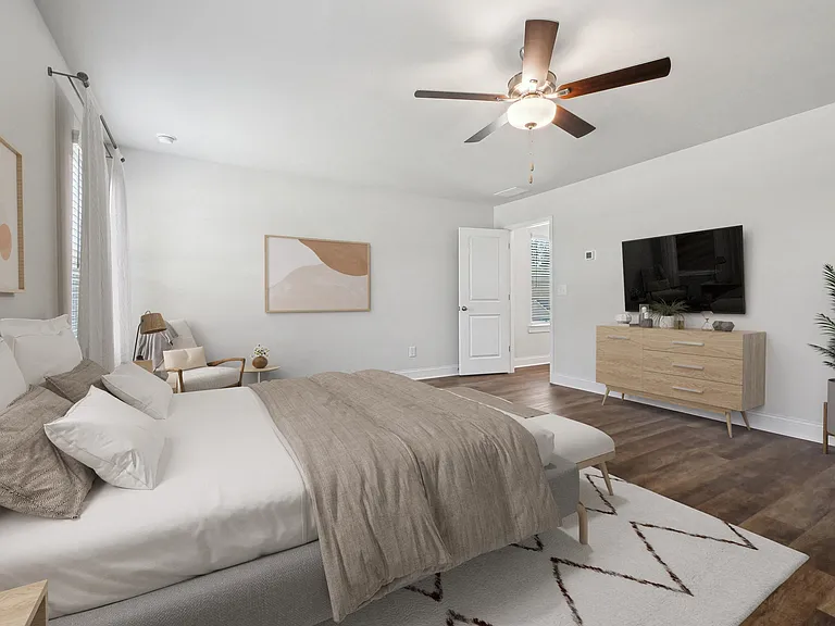 Another view of the spacious primary suite showcasing a grand bed and modern ceiling fan.