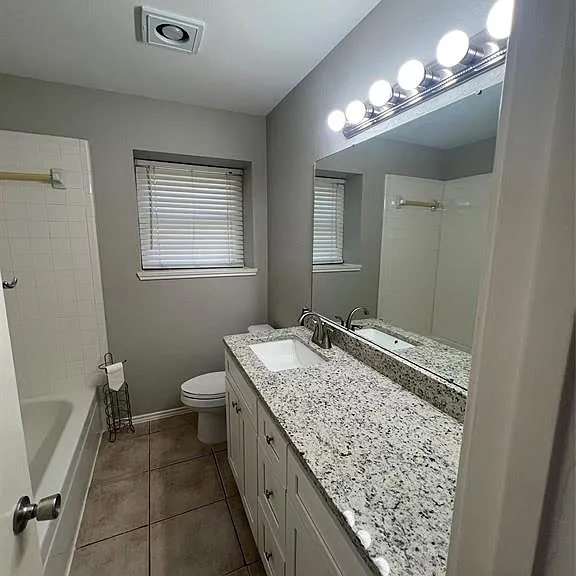 White vanity with brushed nickel hardware, ample countertop space, and large mirror with overhead lighting