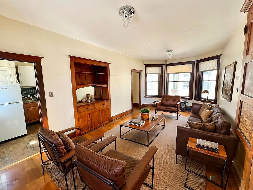 Inviting living room with elegant leather furniture, warm wooden accents, and abundant natural light from large windows.