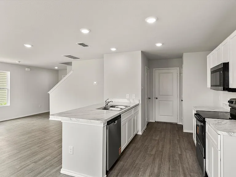 Modern kitchen featuring white cabinetry, integrated appliances, and light-toned countertops