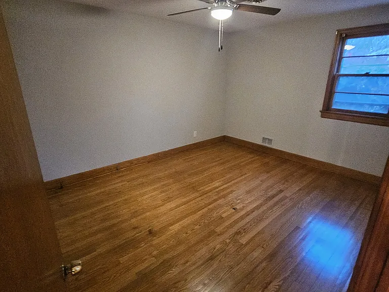 Bedroom with new ceiling fan and wood floors.