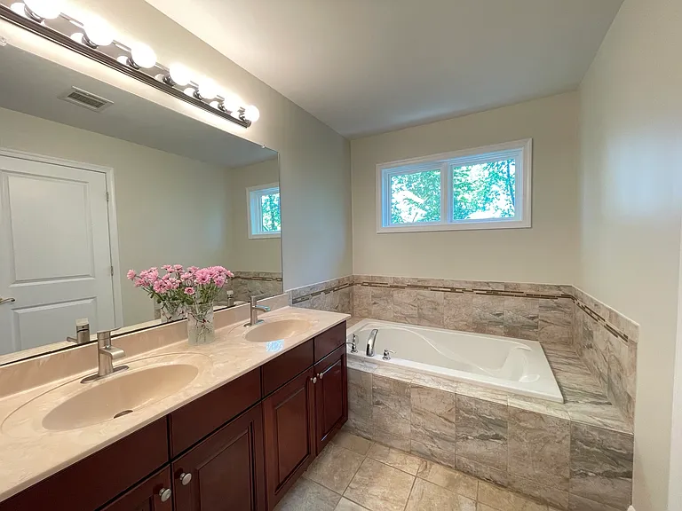 Elegant primary bathroom featuring dual sinks and soaking tub