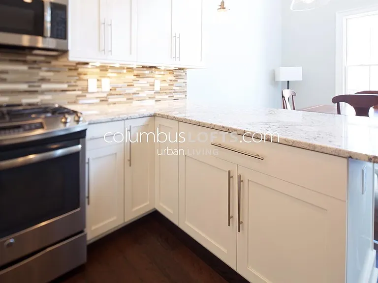 kitchen detail: white granite tops, glass tile backsplash, under-cabinet lighting, high-end appliances