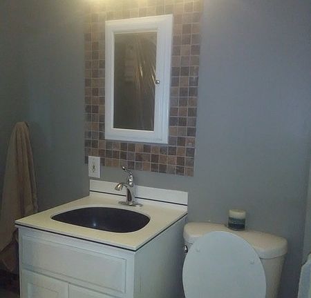 Customized tile work on floor and walls.
						:
						A large, round, rain-style shower head is featured in the shower.