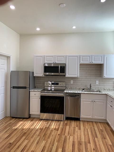 Kitchen Area with Stainless Steel Appliances; Refrigerator, Range/Oven; Microwave, Dishwasher; Sink/Garbage Disposal; Porcelain Tile Back Splash; White Cabinets; LED Dimmer Controlled Ceiling Lighting; Laminated Hardwood Flooring - Left Side View