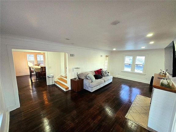 Living area with dark wood-type flooring, crown molding, and recessed lighting