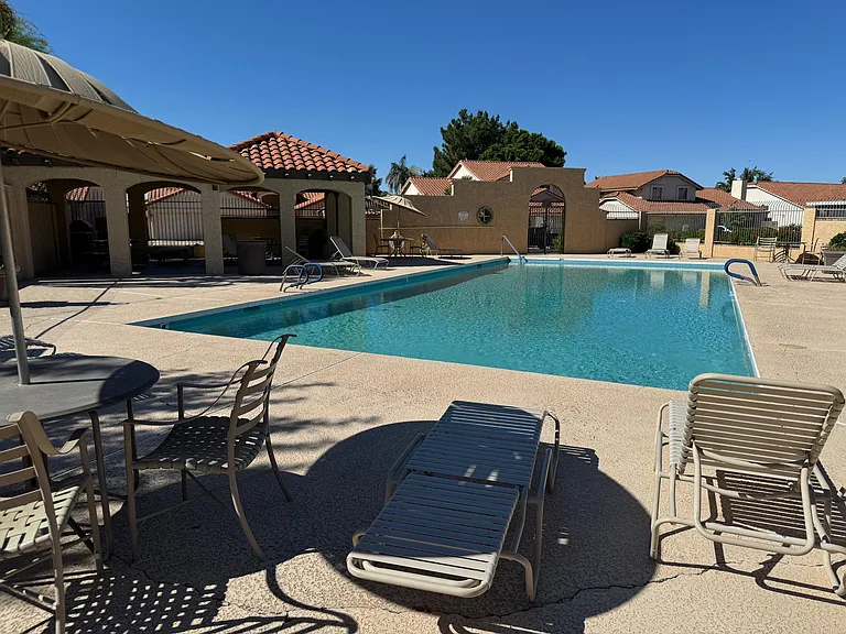 Resort-style pool area with ample lounge seating, shaded patio space, and a large swimming pool for relaxing.
