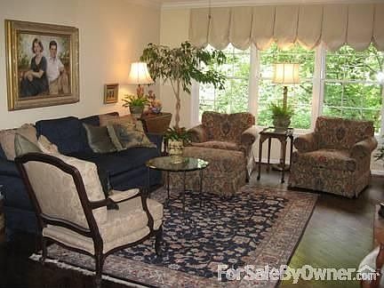 Den with triple windows overlooking large wooded back yard.