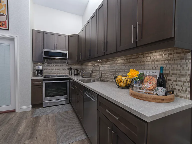 Full kitchen view with dishwasher, oven, cooktop and built-in microwave, with plenty of storage space.