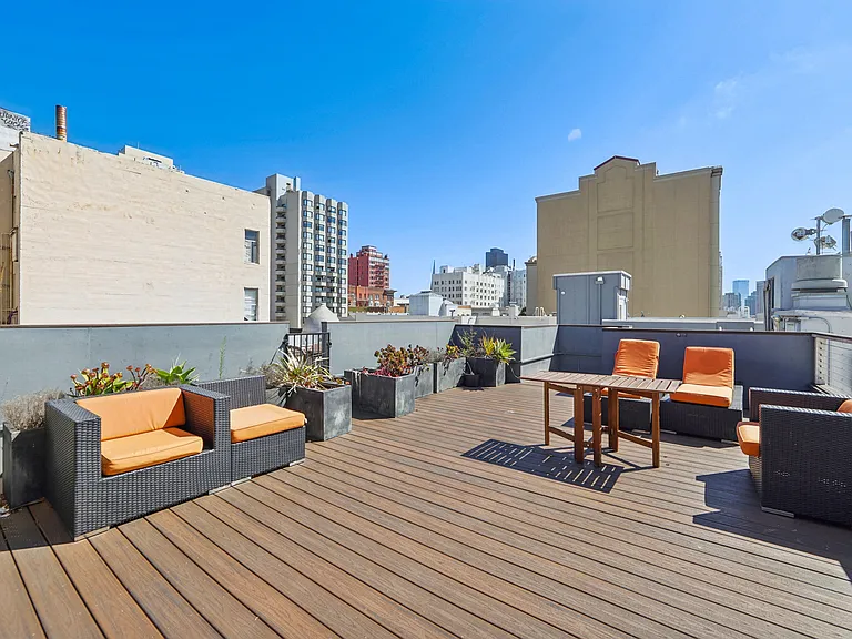 Rooftop patio with lounge chairs, potted plants, and table