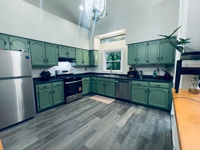Beautifully renovated kitchen featuring updated cabinetry, a new dishwasher, and a new refrigerator. The open layout overlooks a private, nature-filled backyard, offering peaceful views while cooking, dining, or entertaining.