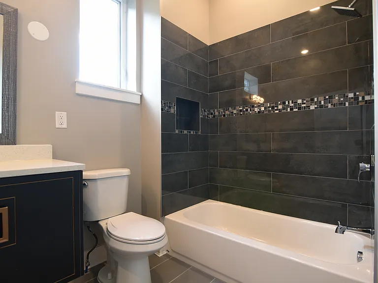 Contemporary tile and design on floor and bath surrounds washer with natural light.