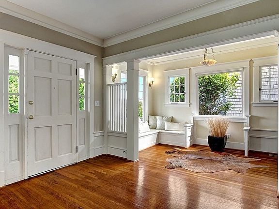 Front entry, with adjacent sitting area featuring wall sconces, window seat, vintage light fixture. 