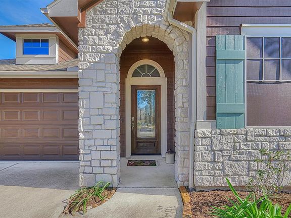 The arched stone faÃ§ade welcomes you to the covered entryway, complete with a leaded glass front door.
