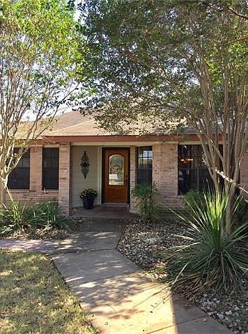Wood front door with 'Star of Texas' design in glass and foliage to shade front of house.