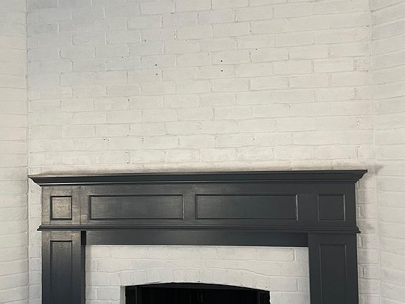 Freshly painted white brick, Sherwin Williams Cyberspace mantle, wood-burning fireplace
