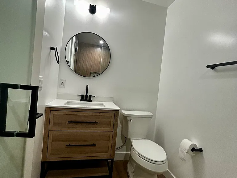 Designer vanity with quartz countertop, modern lighting, and matte black fixtures.
