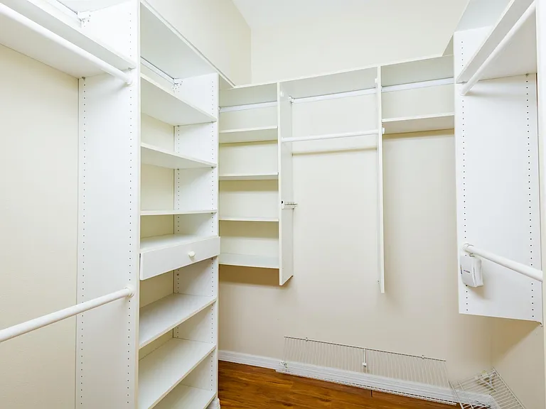 Walk-in closet with wall-mounted wardrobe organizer.
