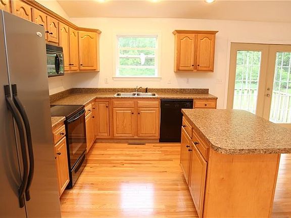 Fully equipped kitchen with custom oak cabinetry, island, hardwood floors, vaulted ceiling, and recessed lighting