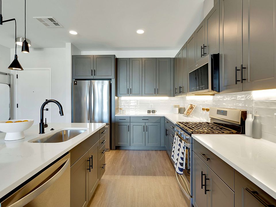 Modern kitchen with sleek grey cabinets, stainless steel appliances, and elegant pendant lighting, offering a bright and inviting atmosphere.