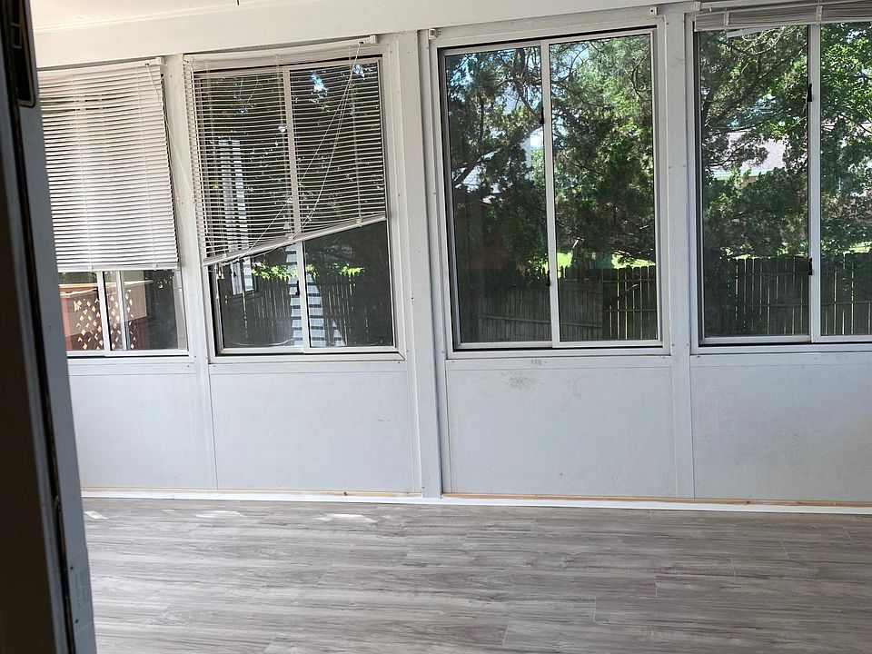 Three season sunroom with new laminate flooring that overlooks backyard with beautiful pine trees