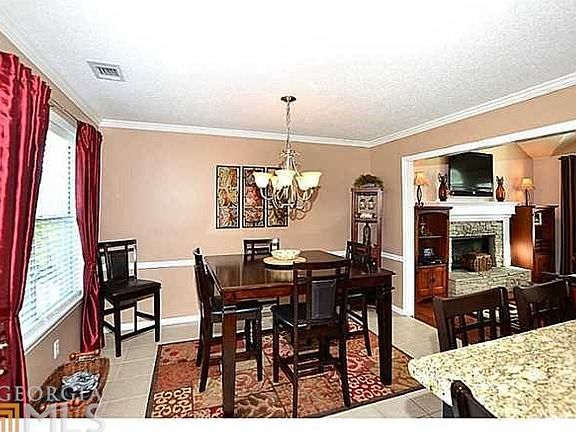 Elegant dining area features tile floors, wall of windows & chair rail detailing - plan your dinner 